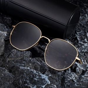Square metal frame sunglasses with dark lenses displayed on a textured grey stone surface