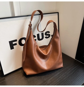 Detail of soft brown PU leather hobo bag showing litchi grain texture and metal zipper