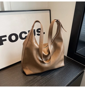 Detail of a brown textured faux leather tote bag with silver zipper and adjustable strap