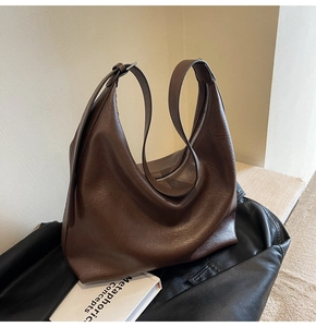 Detail of the adjustable silver buckle and wide strap on the dark brown leather tote bag