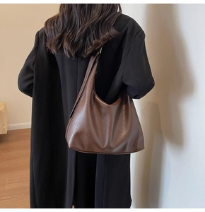 Close-up of a vintage brown leather hobo bag worn by a model in a minimal setting