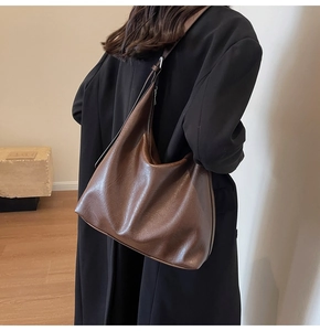Rear view of model wearing a large brown tote bag showing natural leather texture and drape