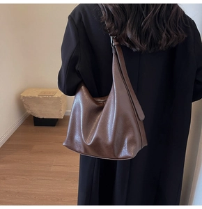 Detail of dark brown vintage wax leather tote bag worn by a model in a minimalist room