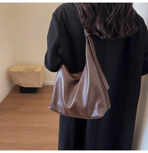 Macro detail of high-quality brown pebbled leather texture on minimalist hobo shoulder bag