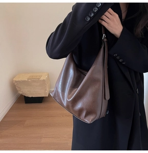 Detail of dark brown faux leather tote bag with soft texture worn on shoulder