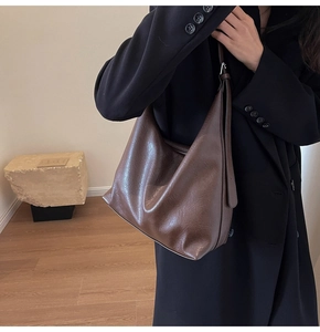 Detail of dark coffee vintage leather hobo bag with adjustable strap on a shoulder