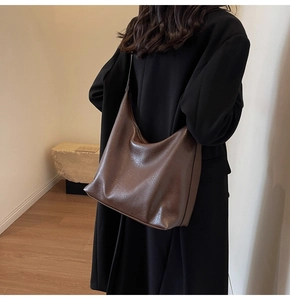 Detail of coffee brown large hobo shoulder bag worn with a black coat for commute