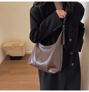 Detailed view of deep brown vintage hobo bag on shoulder with silver hardware