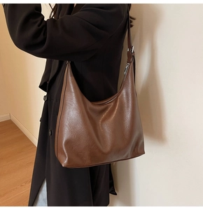 Brown leather crescent hobo bag shown on shoulder for daily commute style