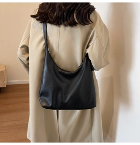 Model wearing a large black matte leather hobo bag with beige trench coat for a casual look
