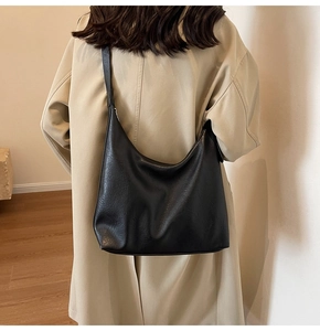 Model view of a large black minimalist hobo bag showing capacity and drape on shoulder