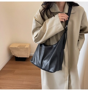 Detail of the black matte leather texture and wide strap on a large tote bag