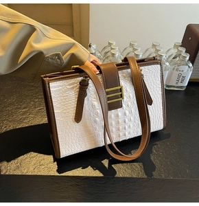 Detail of white crocodile pattern tote with gold metal buckle and brown leather straps