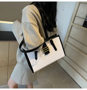 Detail showing white crocodile pattern tote bag with black handles and gold buckle