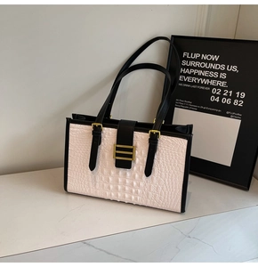 Detail of white crocodile pattern tote bag with black leather straps and gold buckle