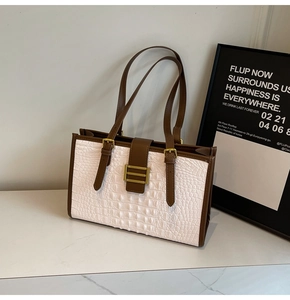Close-up of white crocodile pattern leather shoulder bag with brown strap and gold buckle