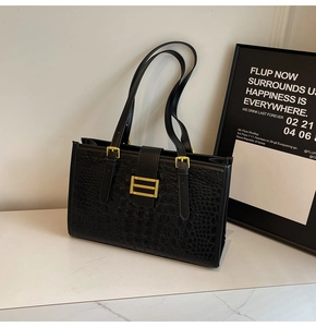 Close-up of black crocodile embossed tote bag with gold metal hardware details