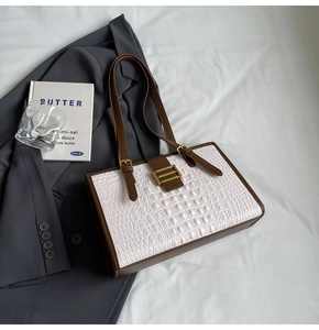 Detail of white crocodile embossed leather handbag with brown straps and gold buckle