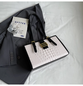 Detail of crocodile texture tote bag with black and white contrast and gold buckle