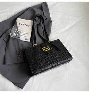 Top view of black crocodile pattern tote bag with gold buckle and fashion props