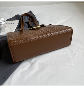 Detail of coffee brown crocodile pattern leather tote showing bottom stitching and texture