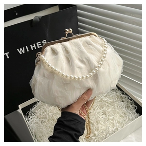 Close-up of white lace pleated evening bag with pearl handle and golden chain