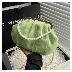 Detail showing light green pleated fabric texture with pearl handle and gold clasp