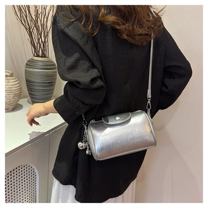 Silberne zylindrische Umhängetasche mit Metallic-Textur an einem Model elegant präsentiert
