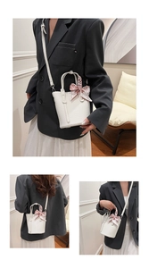 Detail of white bucket bag with lychee texture and decorative pink floral silk scarf