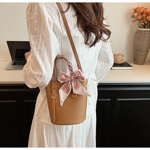 Detailed back view of a brown pebbled leather bucket bag with a pink floral silk scarf