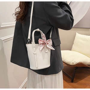 White bucket bag with lychee texture and pink floral scarf detail held by model