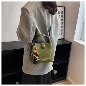 Detail of dark green bucket bag featuring vintage leather texture and rabbit charm