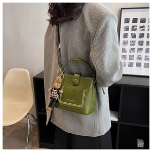 Detail of dark green bucket bag with jacquard strap and plush rabbit charm accessory