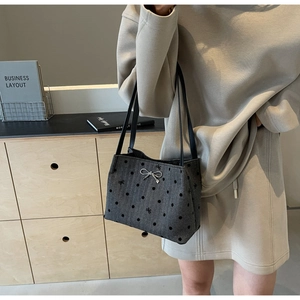 Close-up of a dark grey polka dot bucket bag featuring a silver rhinestone bow charm