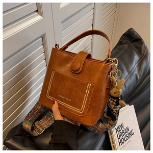 Close-up of vintage brown bucket bag with gold rivets and ethnic pattern strap