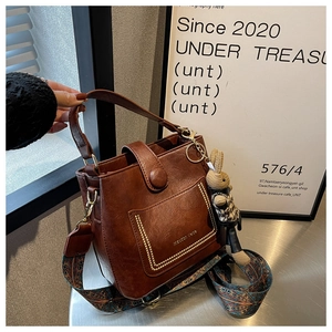 Detail of vintage brown bucket bag with textured faux leather and ethnic woven strap