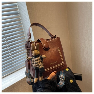 Brown leather bucket bag detail with colorful ethnic strap and a cute rabbit charm