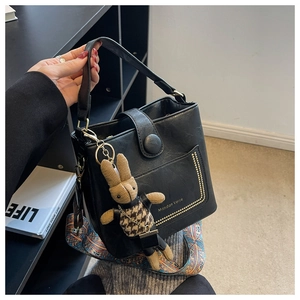 Detail of black vintage bucket bag with gold studs and colorful ethnic strap