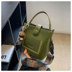 Detail of vintage green bucket bag with textured leather, gold studs, and floral strap
