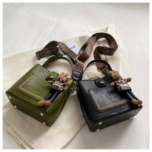 Detail of vintage textured leather bucket bags with wide ethnic straps and charms