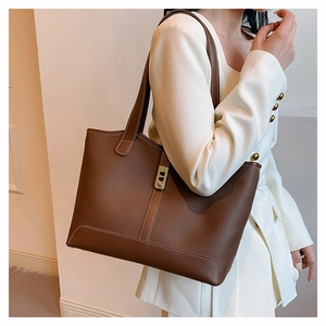 Detail of dark brown leather tote bag featuring gold buckle and white contrast stitching