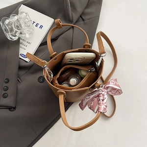 Brown lychee leather bucket bag with printed silk scarf and daily essentials inside