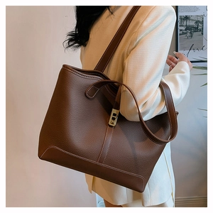Detailed view of brown lychee leather tote bag with white stitching and gold buckle