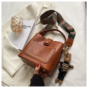 Detail of vintage brown bucket bag with metal rivets and ethnic style wide shoulder strap