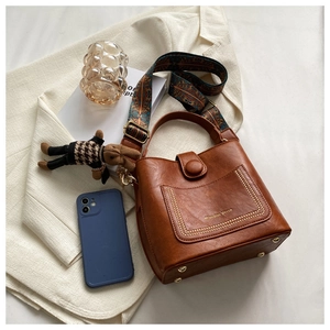 Top view of brown leather bucket bag with rivet pocket and ethnic patterned strap