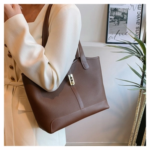 Close-up of brown litchi pattern leather tote bag with white stitching and gold buckle