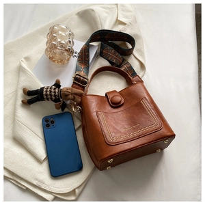 Brown vintage bucket bag with ethnic print strap and rabbit charm on soft fabric