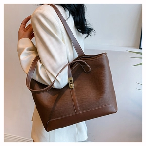 Brown lychee leather tote bag with contrast stitching and golden hardware shown on a model