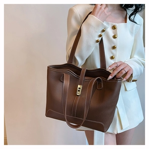 Detailed shot of brown textured leather tote bag with contrast stitching and metal lock