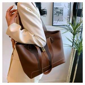 Detail of brown litchi leather tote with white contrast stitching and gold buckle